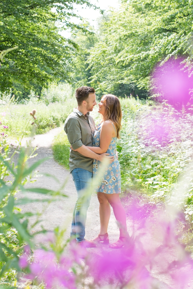 Couple embrace on their engagement shoot in woodland