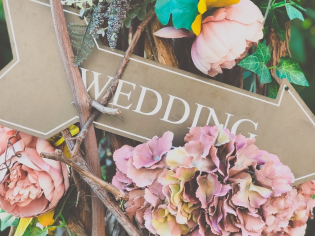 Wedding this way arrow sign in front of wild flowers