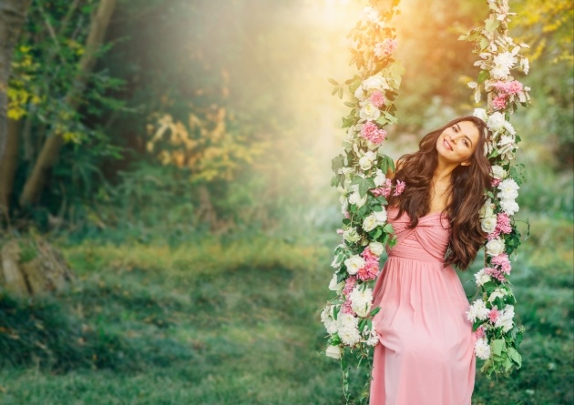 bride in a pink dress on a swing hanging from a tree branch