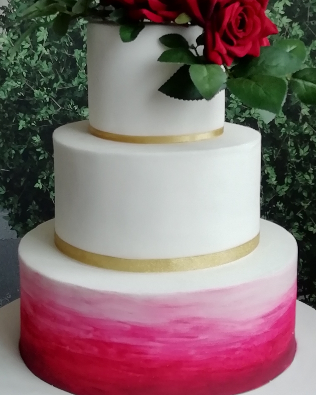 White wedding cakes with a red rose and gradient red bottom tier