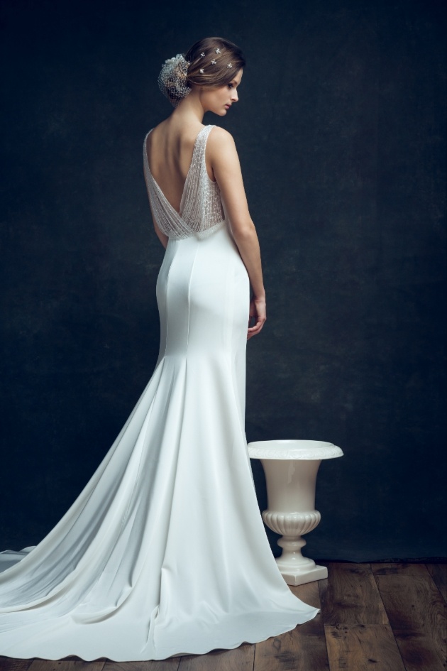bride with back to camera in elegant dress next to Grecian vase