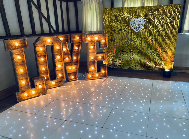 Light up dance floor with glitter wall and love letters for weddings