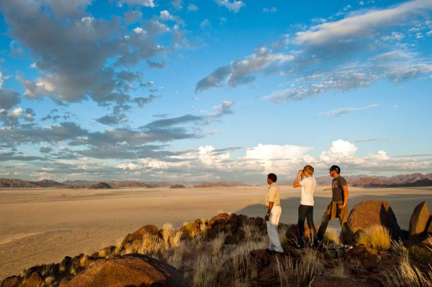 Three male tourists with binoculars in the bush