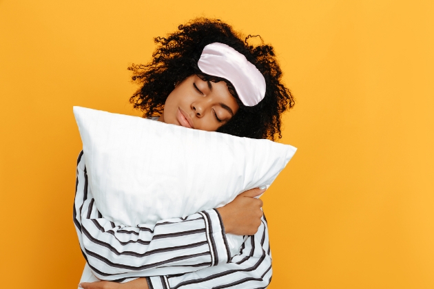 Woman ready for her beauty sleep with pyjamas, sleep mask and pillow
