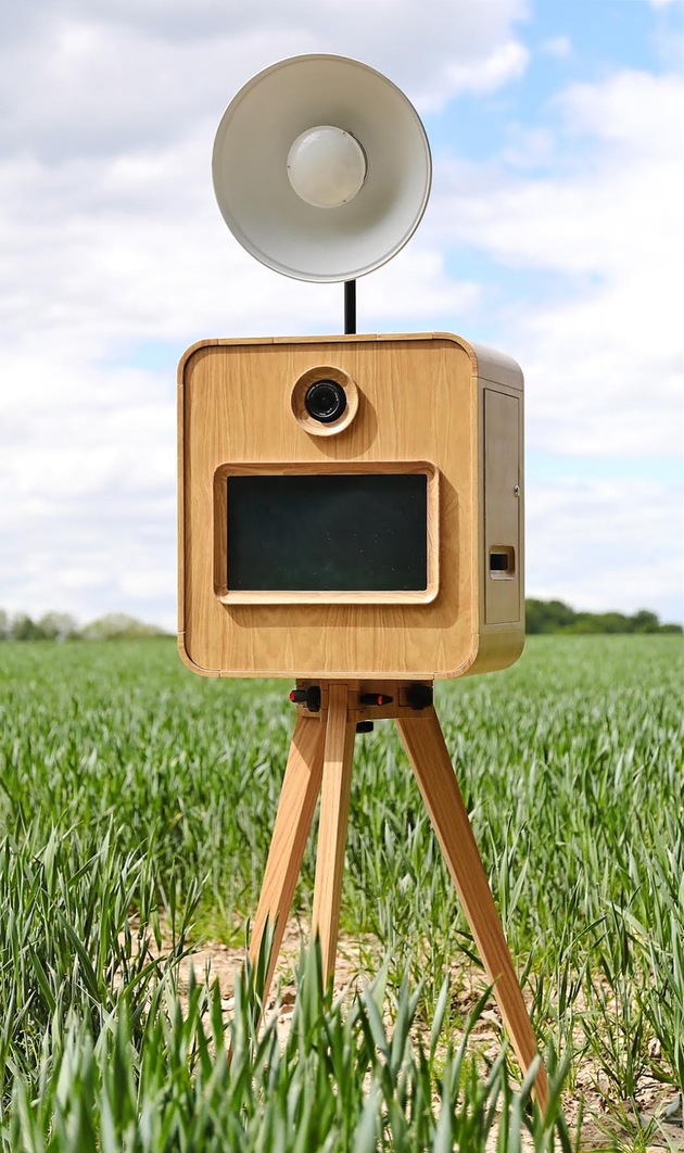 Retro style vintage photo booth stood in field.