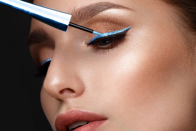 model applying pale blue eyeliner
