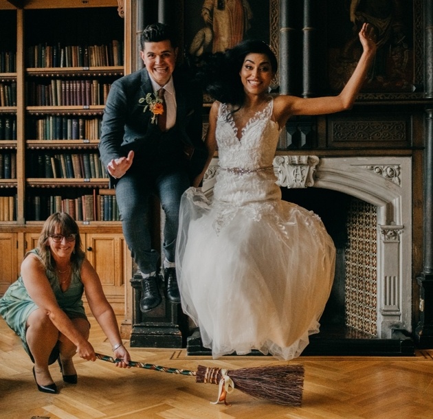 Newlyweds jumping the broom held by wedding celebrant.