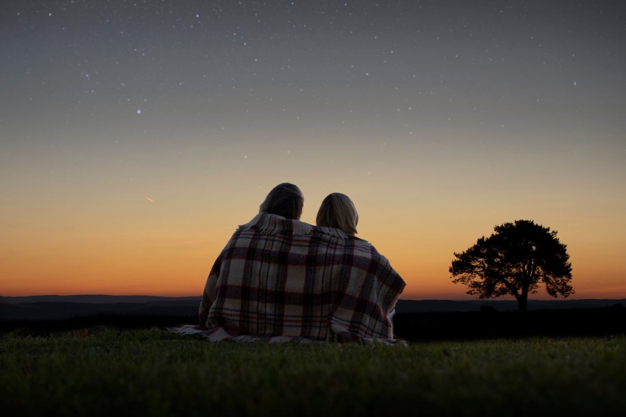 couple in a blanket at night looking at the night sky