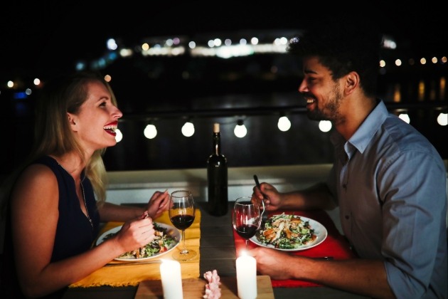 couple having dinner on a balcony at night 