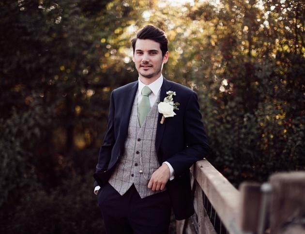 Groom in blue suit with check waistcoat, pocket chain and ivory buttonhole