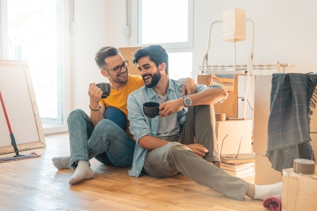 couple sitting having coffee surrounded by moving boxes