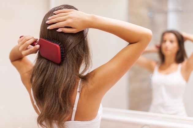 Woman with healthy hair bushing her hair in the mirror