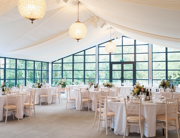 Interior of the Orangery at Baddow Park House wedding venue in Chelmsford with chandeliers and ivory drapes.