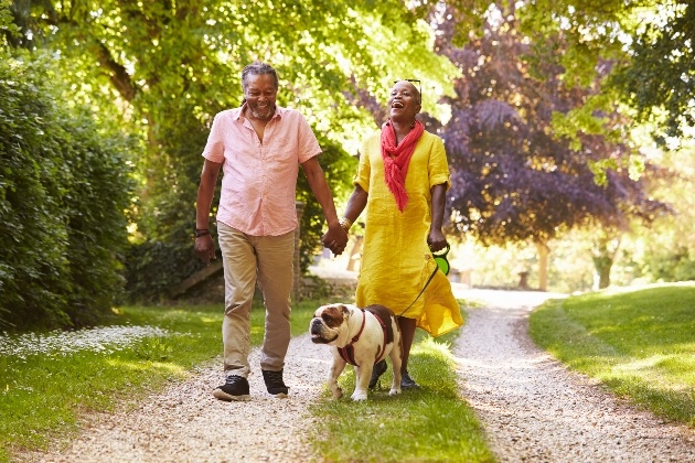 older couple walking dog in park 