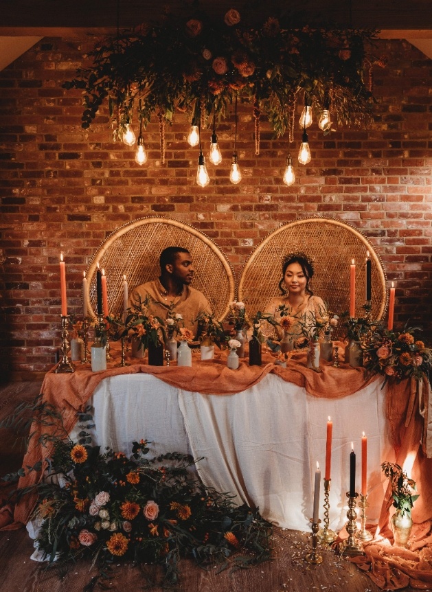 Newlyweds at at sweetheart table decorated with flowers and candles.