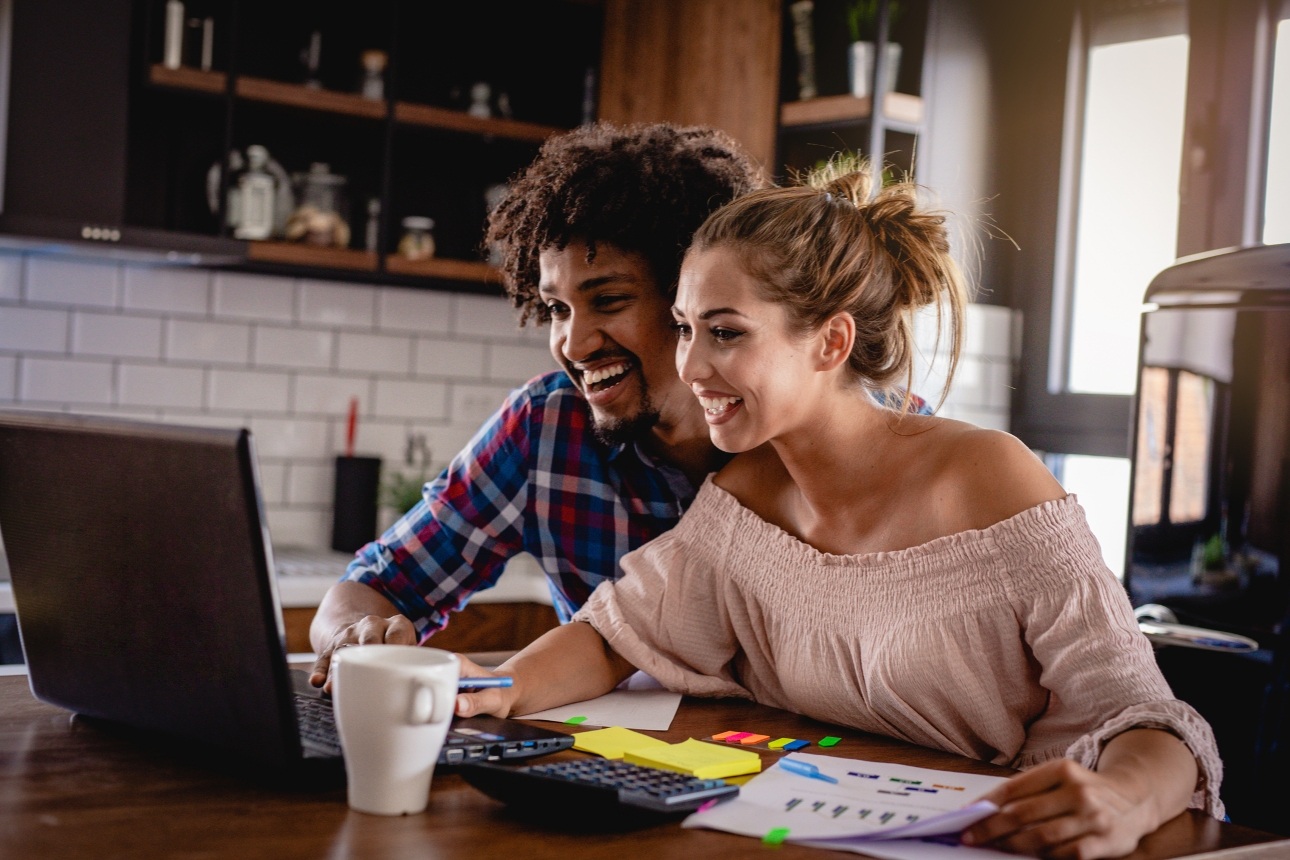 couple together at kitchen table looking at laptop