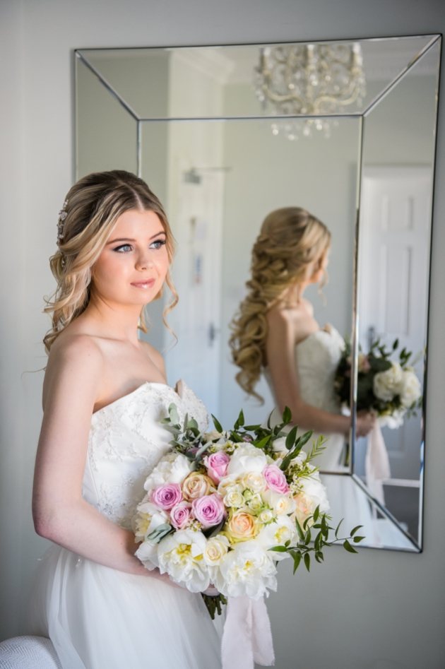 Bride ready for wedding with ivory and pink bouquet.