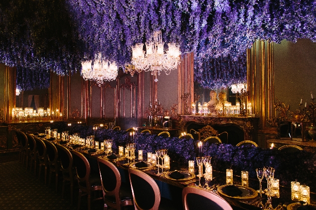 dark room candle lit purple flowers hanging from ceiling 