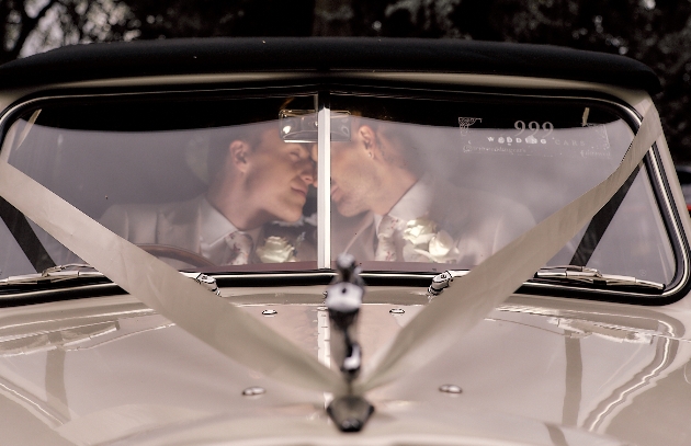 Couple in their wedding car visible through the front windscreen