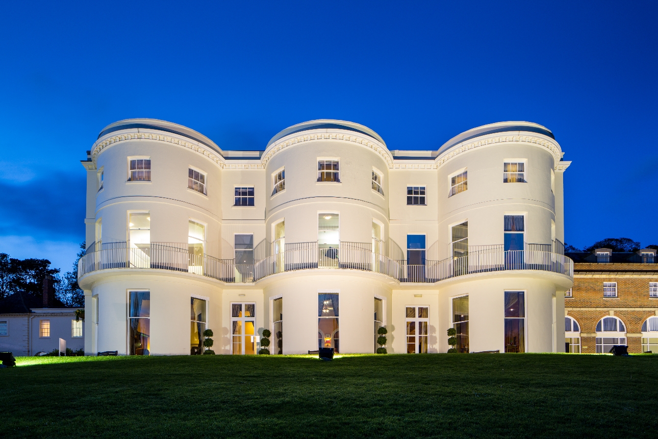 white hotel front at night lit but floodlight