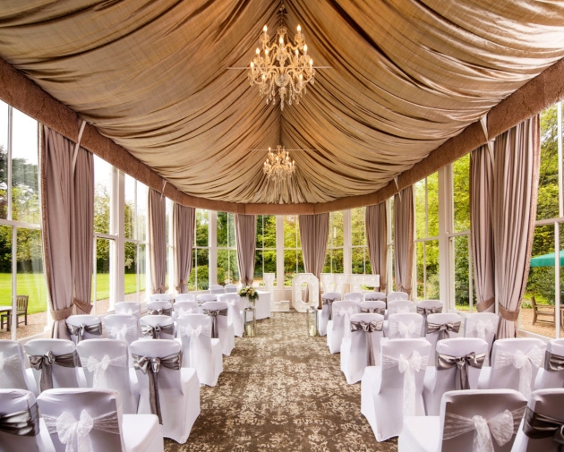 orangery set up for wedding ceremony white chairs and drapes on ceiling