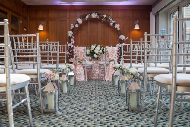 chair set up for ceremony in a wood panelled room with lanterns in aisle 