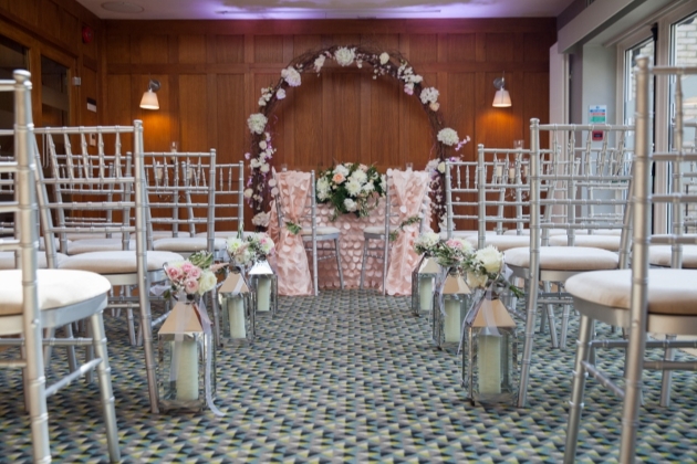 chair set up for ceremony in a wood panelled room with lanterns in aisle