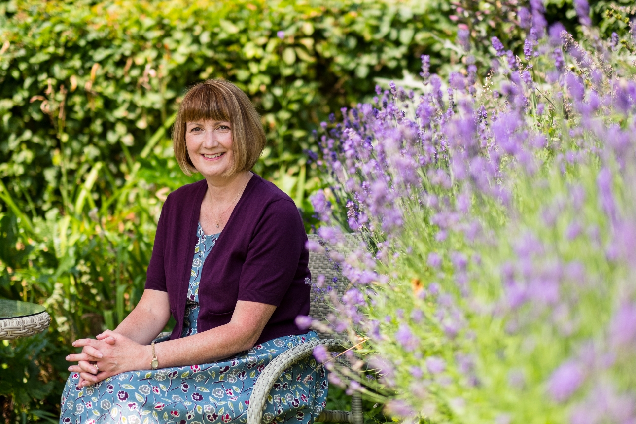 lady sat on a garden chair next to a border of lavender