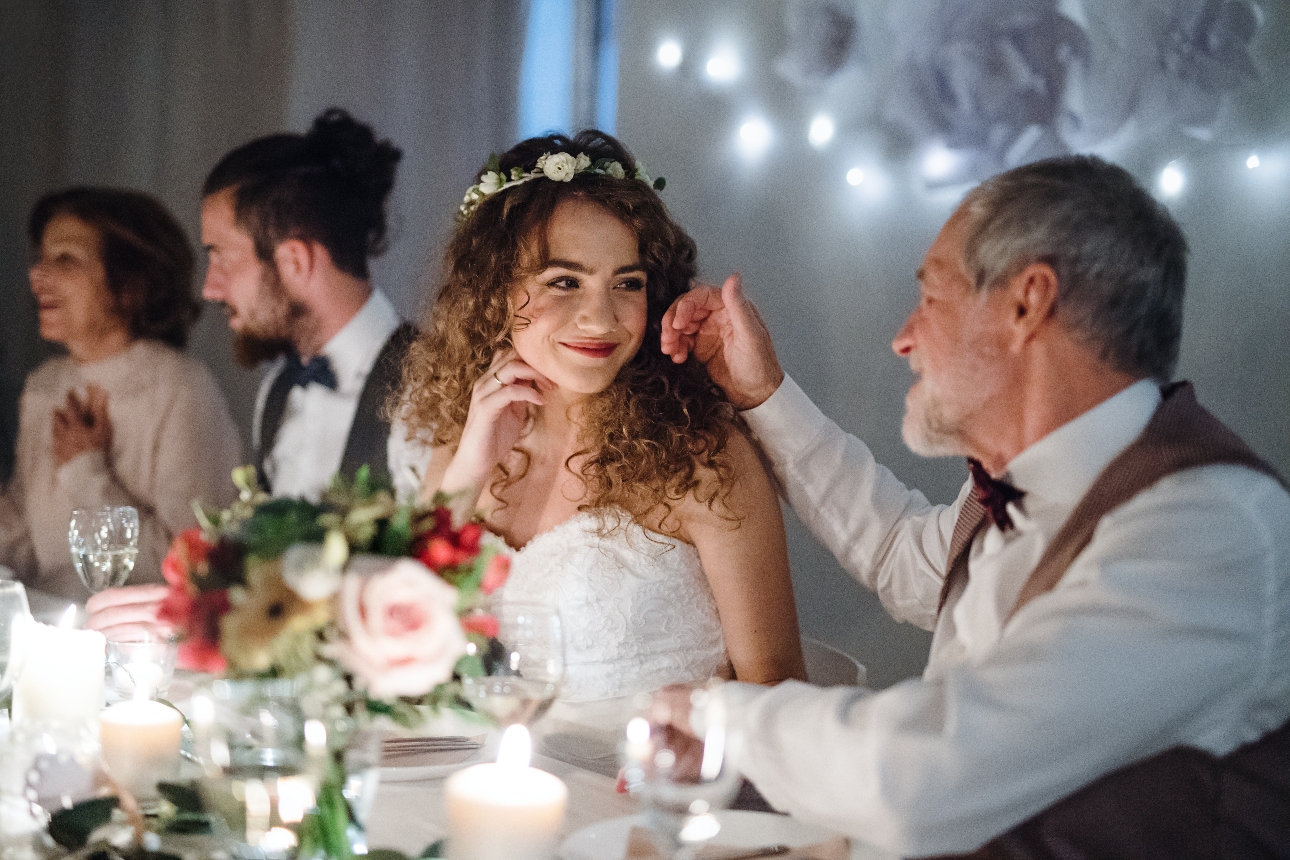 father of the bride with his hand on the brides cheek at the wedding dinner table