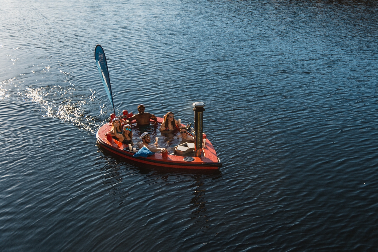 men and women in a hot tub boat on a lake