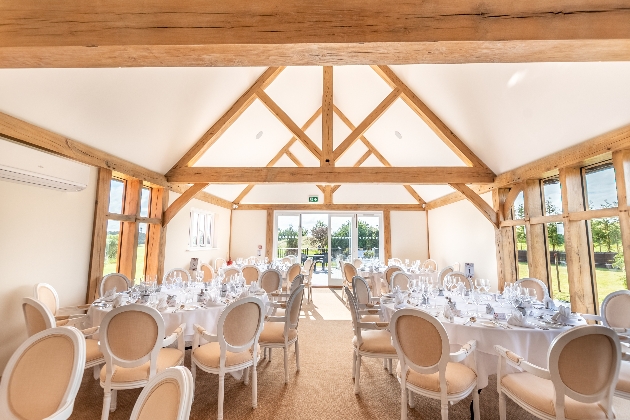 white and cream tables and chairs in a barn style venue with exposed beams