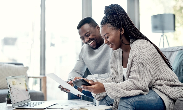 couple sitting on a sofa with laptop and calculator 