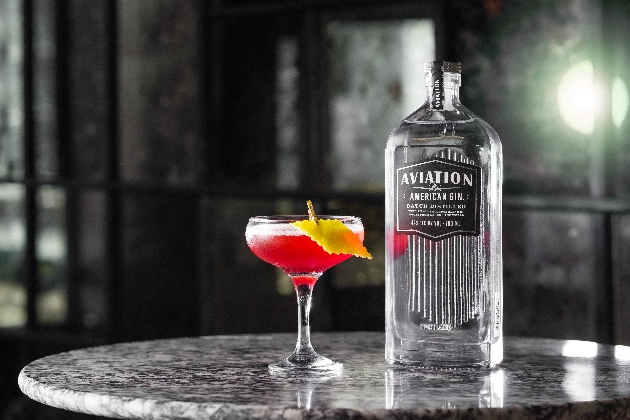 a bottle of Aviation Gin Cosmo gin with a glass of cocktail