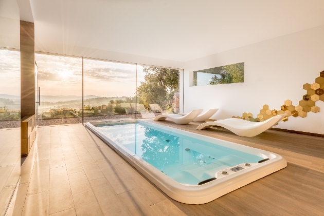 loungers next to hydro pool with panoramic window with hills views