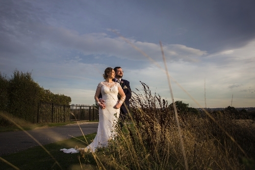 Bride stands in front of groom looking out at the coast