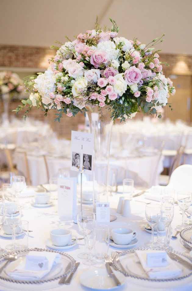 Table with tall glass centrepiece and flowers