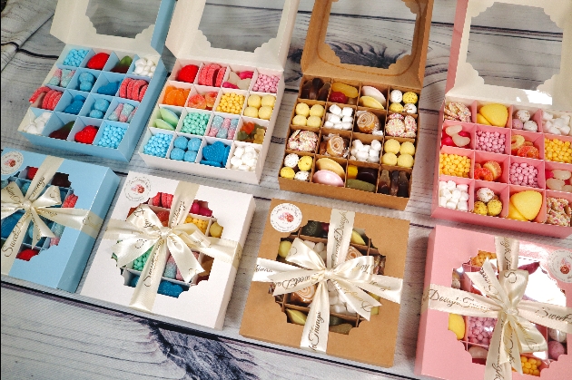 four boxes of different coloured sweets with a bow and clear window lid