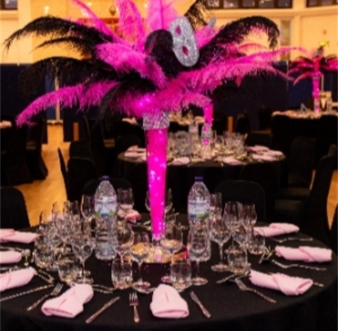 pink and black feathered centrepiece on a table with black cloth