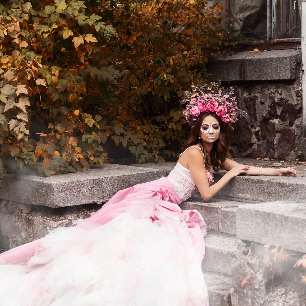 alternative bride with day of the dead make up draped on stone steps in a wedding dress