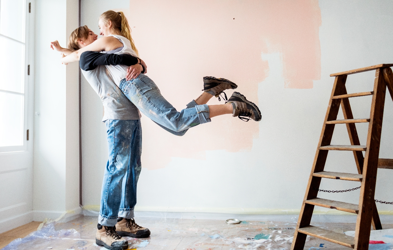 couple hugging in a room with paint on the walls and ladder 