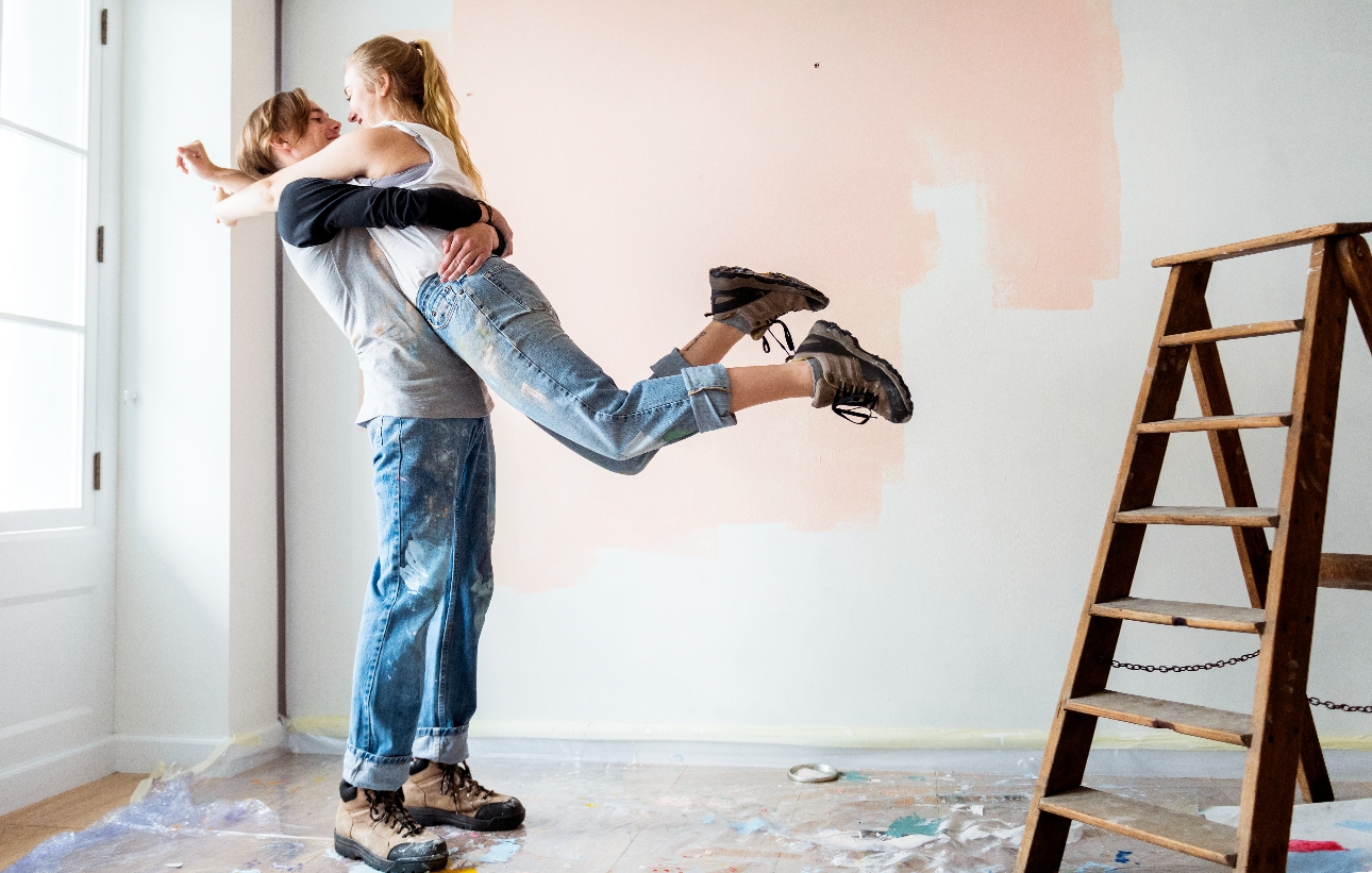 couple hugging in a room with paint on the walls and ladder