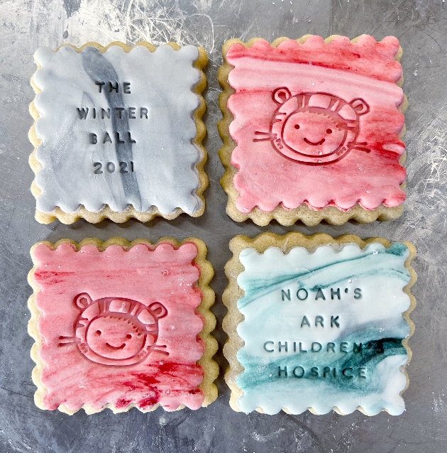four square biscuits together, one grey, on blue and two pink in colour with logos and a tiger print