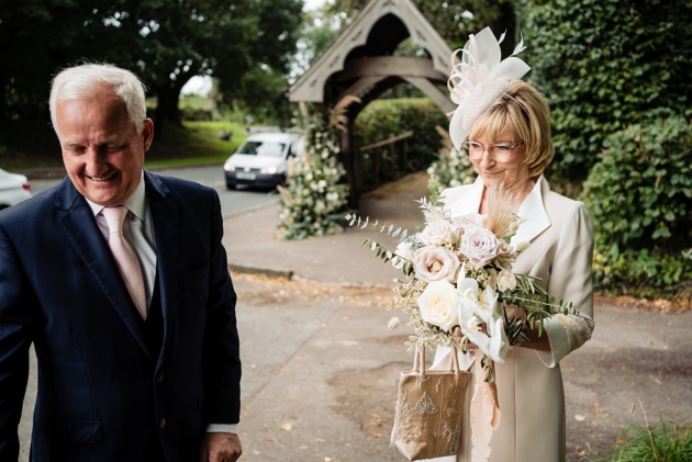 mother of the bride standing outside church with flowers