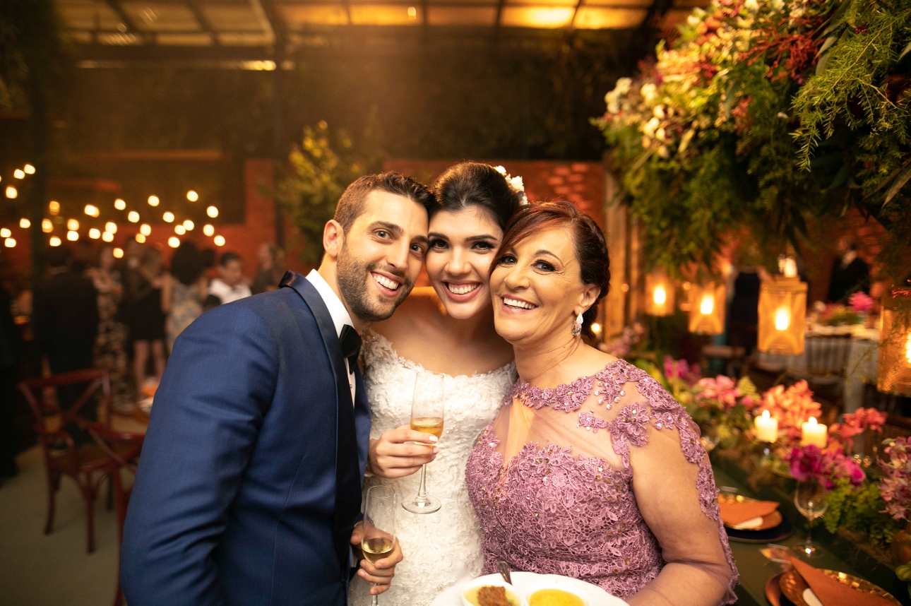 bride and groom standing with a mum at the wedding reception