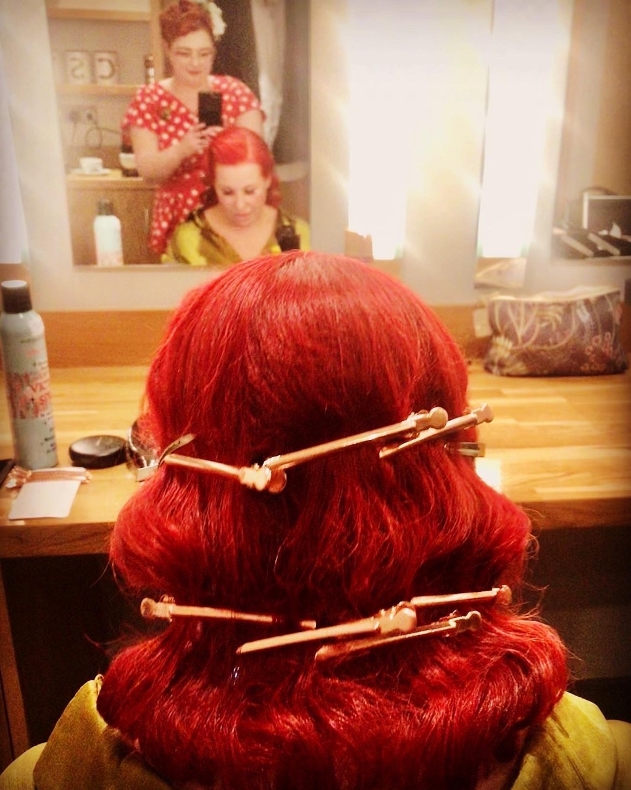 stylist creating a vintage hair do on a red hair model