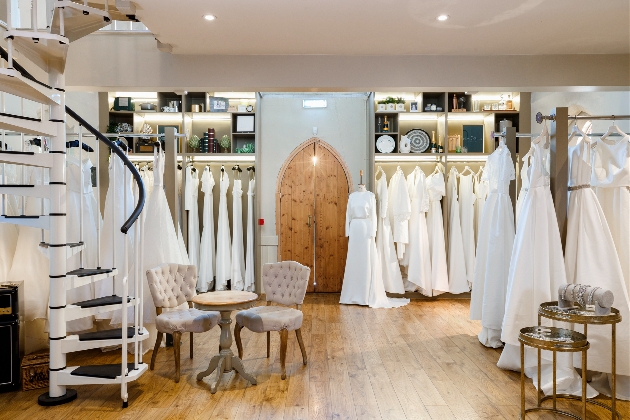 inside a wedding dress shop in rustic barn rails of dresses around 