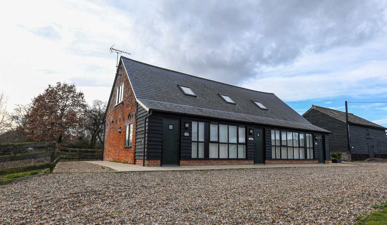 brown and brick barn-like buildings with gravel drive