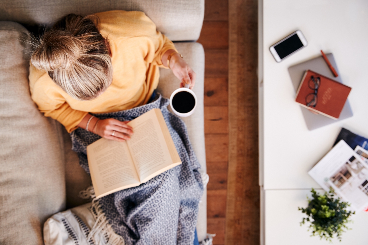 woman sat on sofa reading book