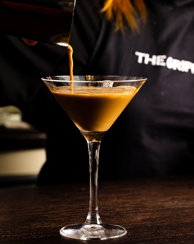 Espresso martini in a glass with a bar tender pouring in liquid