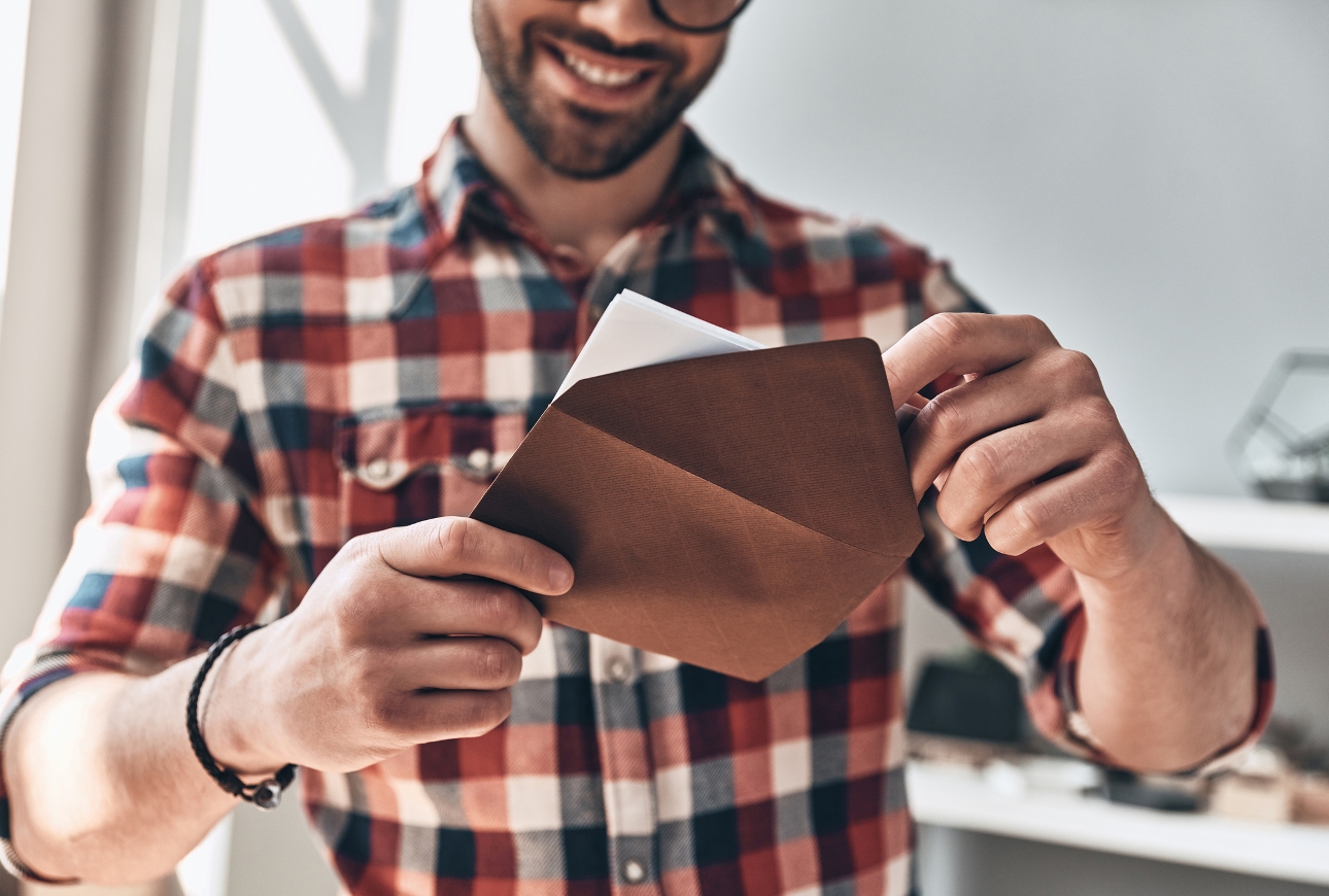 man in red check shirt opening and envelope